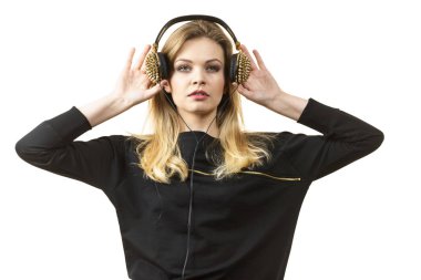 Genç grunge kadın siyah giyinmiş ve sivri uçlu kulaklıkla müzik dinliyor.