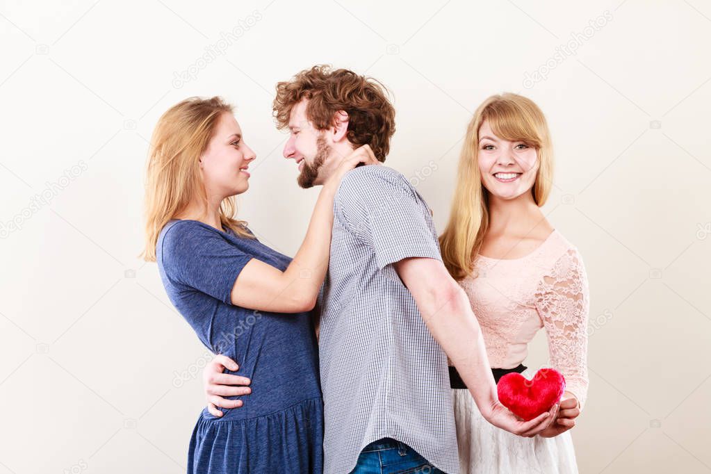 Betrayal and infidelity concept. Handsome boy with two attractive blondie girls. Man cheating women by mislead chosen one and offer his heart to another.