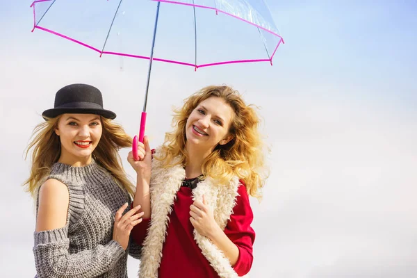 スタイリッシュな衣装を身に着けている2人のファッショナブルな女性透明な傘を保持しています彼らの自由な時間屋外 — ストック写真