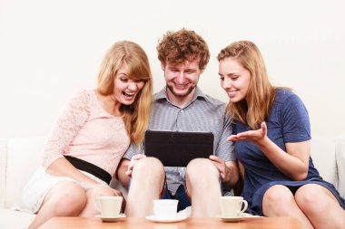 Tarama arkadaşlar dalga köpüğü enterne tablet üzerinde. Gençler evde kanepe rahatlatıcı oturan adam ve kadın kız adam.