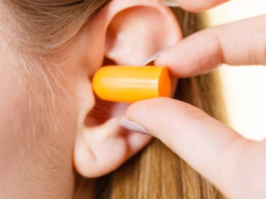 Yüksek sesle yerinde gürültü kurtulmak onun kulaklarına kadın koyarak kulak tıkacı.