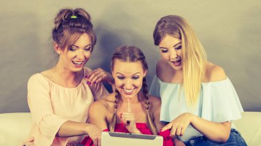 Eğleniyor koltukta oturan kadınlar akıllı dijital pc tablet modern cihaz kullanarak internette sörf