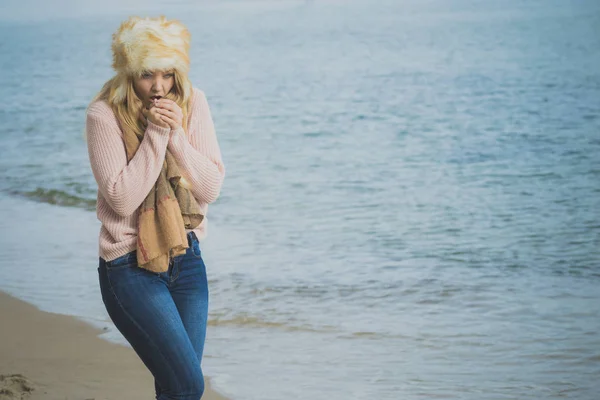 まだ寒さを感じる毛皮の大きな帽子と暖かいスタイリッシュな秋の衣装を身に着けている女性 ビーチでリラックスしながら寒さを持つ女性 — ストック写真