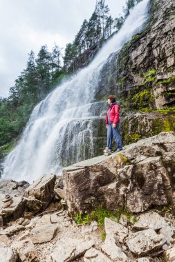 Norveç 'teki Svandalsfossen' de turist bir kadın Norveç dağlarında güçlü bir şelale. Ulusal turist Ryfylke güzergahı.