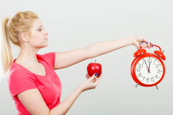 Счастливая женщина держит часы, яблоко и измерительную ленту — стоковое фото