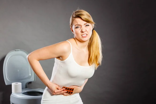 Woman suffer from belly pain holds pills in toilet — Stock Photo, Image