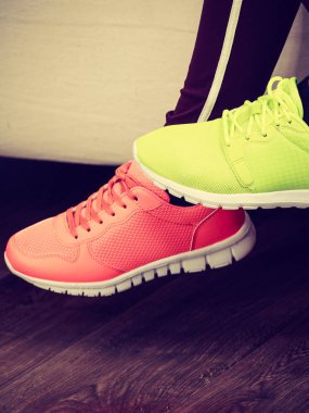 İki tanınmaz halde kadın spor ayakkabı giyen, yeşil kırmızı ve neon olanlar. İş kıyafeti parçaları.