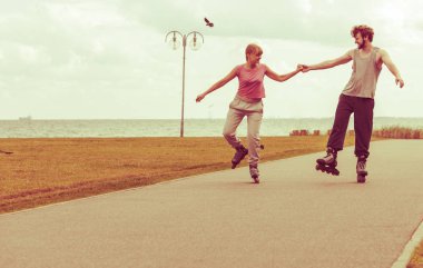 Aktif yaşam tarzı ve özgürlük kavramı. Deniz kıyısında paten süren genç ve zinde bir çift, kadın ve erkek birlikte vakit geçiriyorlar..