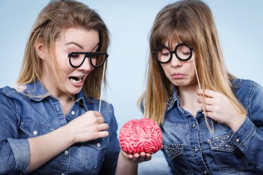 Dostluk, insan ilişkileri kavramı. İki deli kadın arkadaşlar veya kot gömlek ve gözlük sopa üzerinde giyen kız sorun holding sahte beyin çözme hakkında düşünme