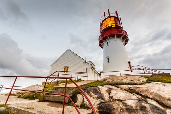 Kayalık deniz Sahili, Güney Norveç, Lindesnes Fyr feneri kenarında tarihi kırmızı beyaz deniz feneri