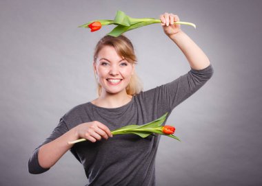 Bahar zamanı. Delilik ve eğlenceli bir kavram. Oynak mutlu kız çiçekleri ile oynuyor. Lale ile deli rakamlar yapma sevinçli gülümseyen komik pozitif kadın kişi.
