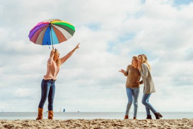 Birlikte harika vakit geçiren üç kadın. Renkli bir şemsiye tutan bir kadın.