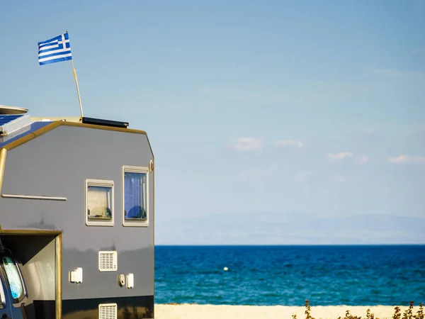 Camping truck on beach with Greek national flag on roof. Traveling, adventure concept.