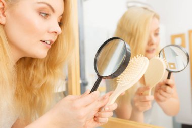 Büyüteç kullanan kadın fırçasına bakıyor. Saç dökülmesi, saç bakım konsepti..