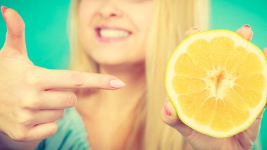 Sarı greyfurt yarısı narenciye meyve elinde tutan, parmakla işaret, sağlıklı beslenme, yeşil tavsiye kadın gülümseyen kız. Diyet kaybetme ağırlık kavramı.