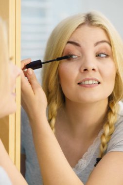 Makyajını siyah rimel sürerek yapan bir kadın kirpiklerini fırçalıyor. Kadın güzellik çehresi konsepti.