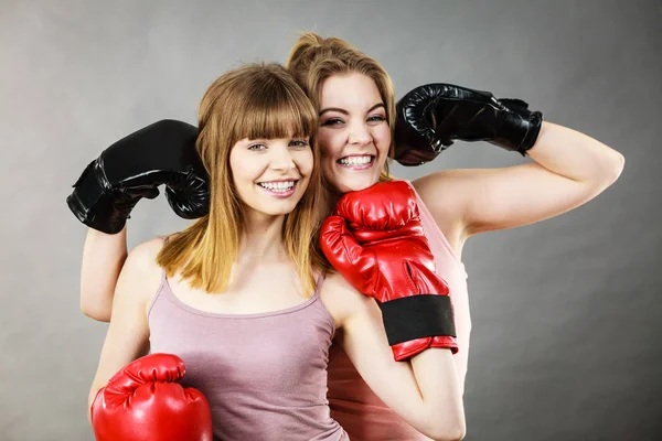 Friendship, human relations concept. Two happy women friends having fun smiling with joy wearing boxing gloves being fit and sporty.