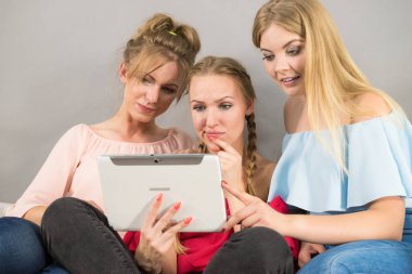 Eğleniyor koltukta oturan kadınlar akıllı dijital pc tablet modern cihaz kullanarak internette sörf