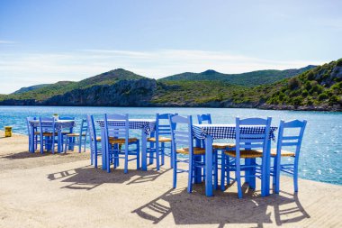 Deniz kenarındaki mavi masa ve sandalyeler deniz kıyısında Yunanistan 'da açık bir kafe restoranı açıyor. Yaz tatili.
