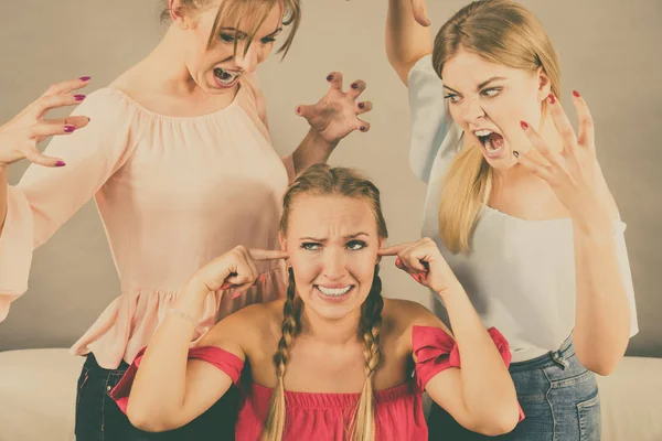 Woman being bullied by her two female friends. Women having argument. Angry fury girls screaming at her friend or younger sister. Friendship difficulties, rivaly and envy problems.