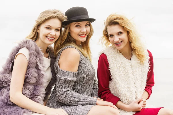 Three fashionable women having presenting pretty stylish outfits. Style, fashion, friendship concept.
