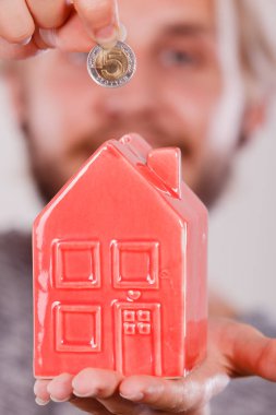 Ev tasarruf ve finans, ekonomi kavramı. Kumbara house, gri arka plan üzerinde atış stüdyo olarak para madeni para koyarak adam