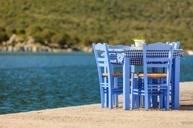 Deniz kenarındaki mavi masa ve sandalyeler deniz kıyısında Yunanistan 'da açık bir kafe restoranı açıyor. Yaz tatili.