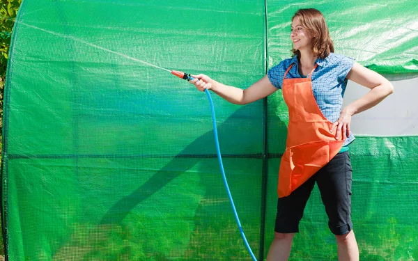 Berkebun Perempuan Celemek Oranye Memegang Selang Sprinkler Untuk Irigasi Tanaman — Stok Foto