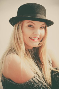 Gökyüzü arka plan üzerinde poz güzel sarışın genç kadın giyiyor fedora şapka ve kazak jumper.