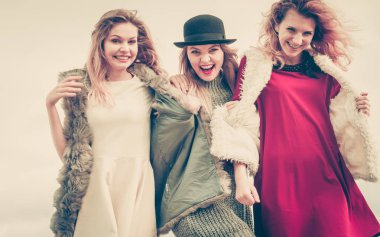 Üç modaya uygun kadın şık kıyafetler giyiyorlar. Tarz, moda, arkadaşlık konsepti.