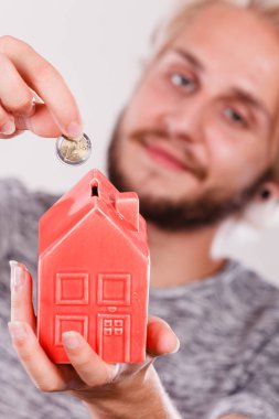 Ev tasarruf ve finans, ekonomi kavramı. Kumbara house, stüdyo ışık arka plan üzerinde atış şeklinde para madeni para koyarak adam