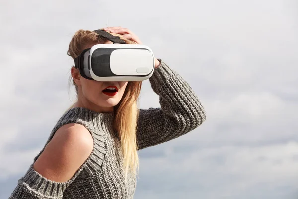 Young woman testing VR glasses outside. Female wearing virtual reality headset during spring weather,