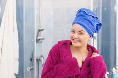 Banyoda duş aldıktan sonra havluyla ve bornozla kendini rahat hisseden genç bir kadın.