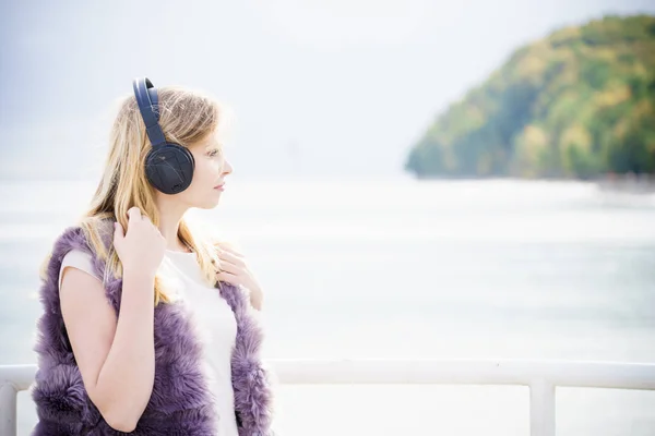 リラックスした女性が屋外でありながら音楽を聴きます 外ゾッと素晴らしい時間を過ごしているヘッドフォンを身に着けている 代の女性 — ストック写真