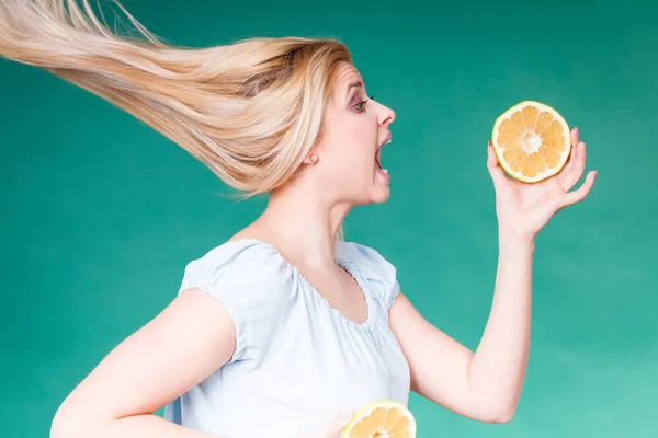 Healthy diet, refreshing food full of vitamins. Woman with open mouth holding sweet delicious citrus fruit, orange grapefruit, she wants to take bite.