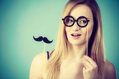 Karnaval accessoies eğleniyor çubuğa tutan kadın. Mavi arka plan üzerinde atış stüdyo.