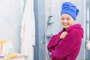 Banyoda duş aldıktan sonra havluyla ve bornozla kendini rahat hisseden genç bir kadın.