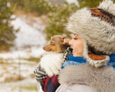 Genç bir kadın soğuk kış gününde en iyi arkadaşını sıcak battaniye eşarbına sardı. Hayvan koruma programı. Evlat edinme kavramı