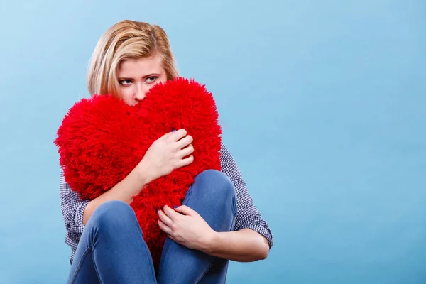 Break up, divorce, bad relationship concept. Sad, depressed woman holding big red fluffy pillow in heart shape, she needs love.