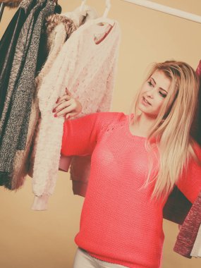 Moda tarzı, modaya uygun kıyafetler, giysi konsepti. Sarışın kadın gardıropta durmuş, mükemmel bir kış kıyafeti seçiyor..