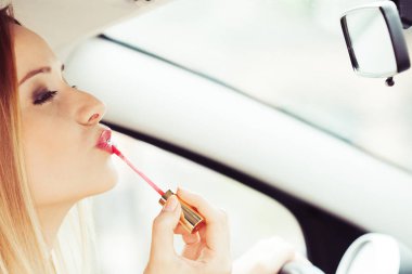 Deli sürücü. Dikiz aynası dudaklarını araba sürüş sırasında uygulanan makyaj yapıyor boyama arayan genç çekici kadın.