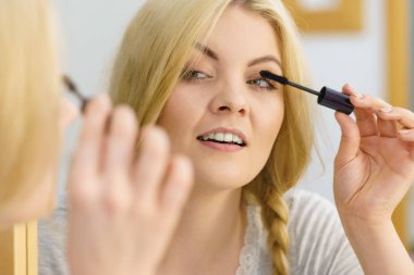 Makyajını siyah rimel sürerek yapan bir kadın kirpiklerini fırçalıyor. Kadın güzellik çehresi konsepti.