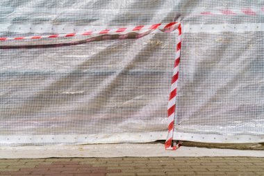 İnşaat alanında tehlike uyarısı kaseti. Açık kumaşta kırmızı ve beyaz şerit.