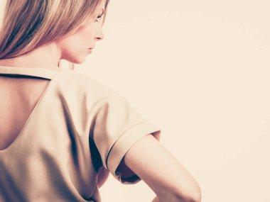 Tanımlanamayan bir kadın moda pembe bluzunu sırtında delik detaylarıyla sunuyor..