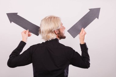 Planlama, yön, seçimler kavramı. Siyah ok sol ve sağ yukarı, tam aksi istikametinde işaret tutan adam. Açık renkli üzerinde kapalı atış