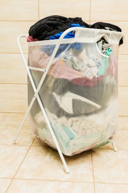 Renkli kirli çamaşırlarla dolu şeffaf beyaz bir çamaşır sepeti. Banyo aletleri konsepti.