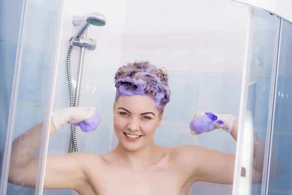 女人戴着乳胶防护手套 同时在她的金发上涂紫色扁桃体洗发水 在家理发的概念 — 图库照片