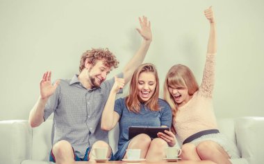 Tarama ayarlarý el ile başarılı mutlu arkadaşlar dalga köpüğü enterne tablet üzerinde. Gençler evde kanepe rahatlatıcı oturan adam ve kadın kız adam.