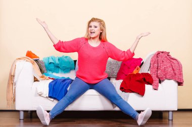 Giyim ikilemler kavramı. Kadın giysileri yığınları ile dağınık kanepede oturan giymek için ne bilmiyorum.