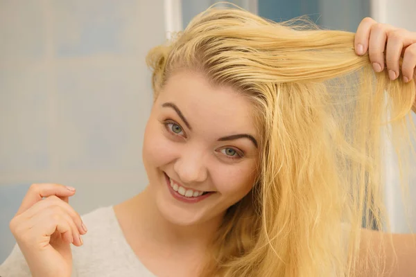 Happy woman having wet blonde hair. Positive clean female after taking a shower feeling clean and relaxed.